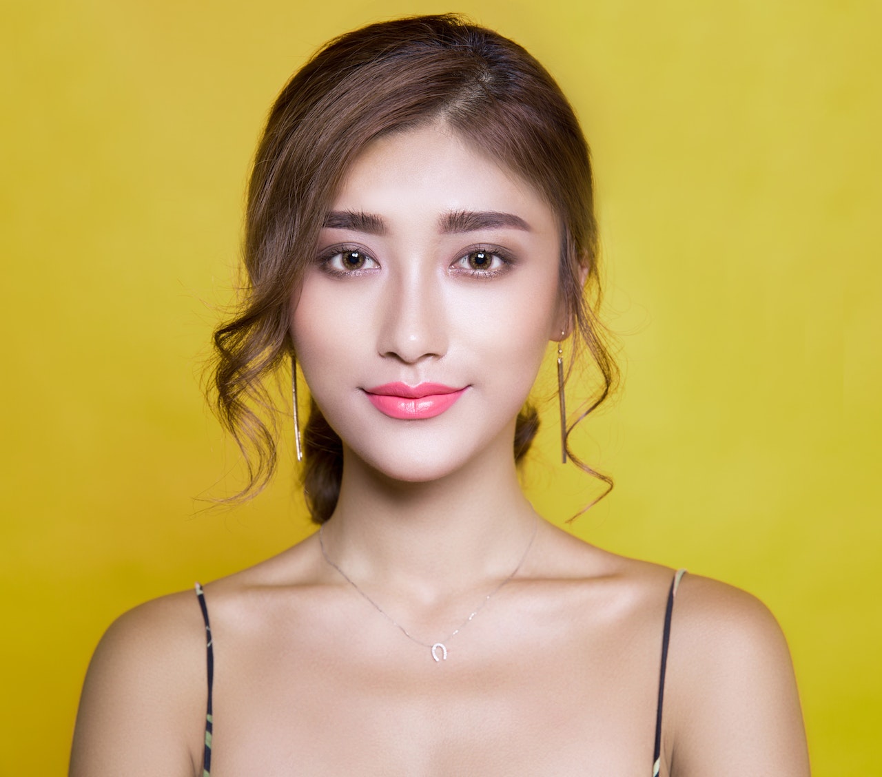 Asian woman posing for a photo on a yellow background.