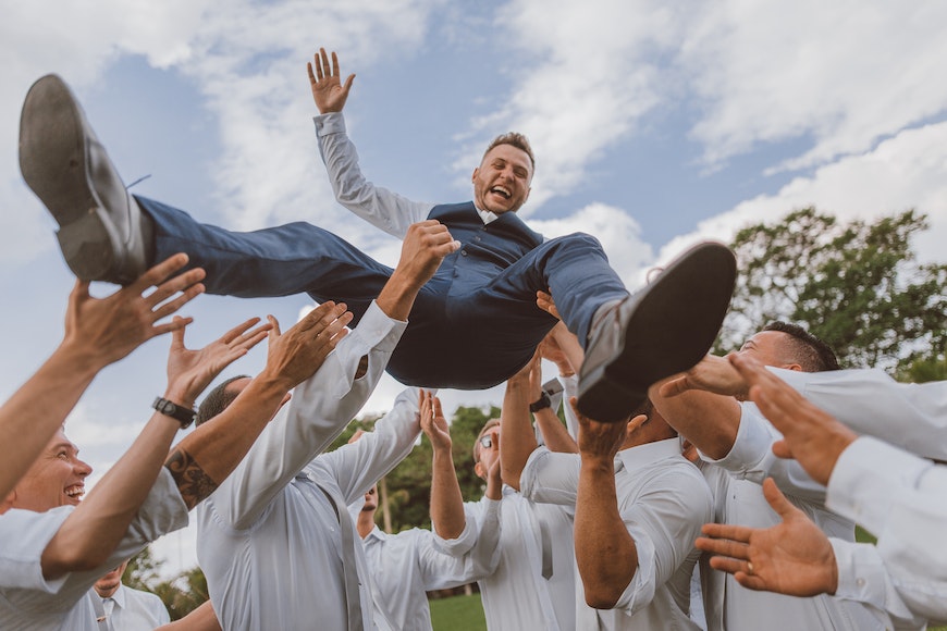 A groom being thrown into the air by his groomsmen.