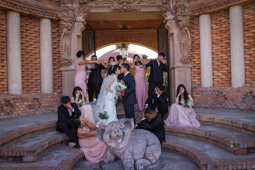 A wedding party posing in front of a lion statue.