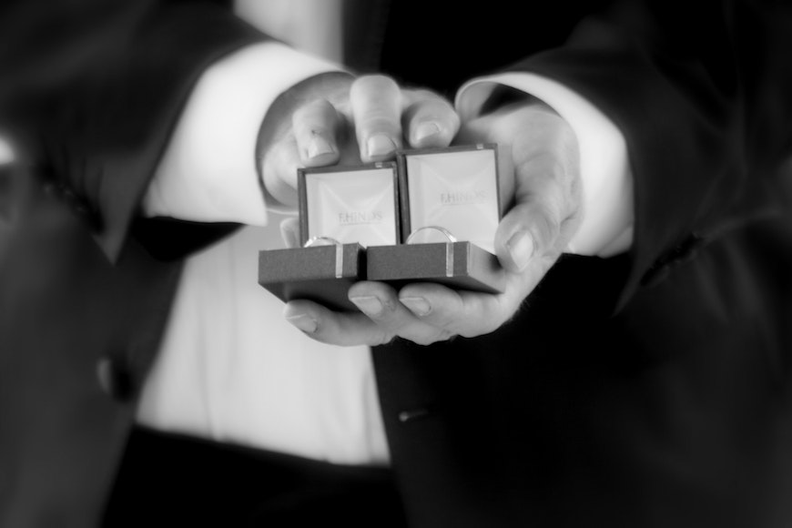 A black and white photo of a man holding a wedding ring.