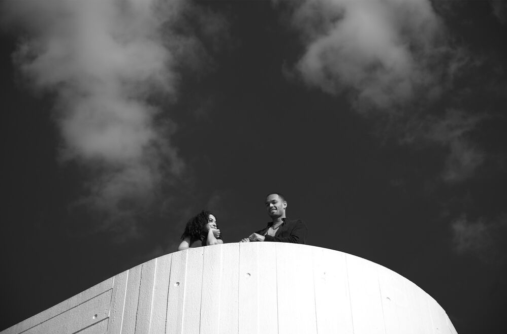 A black and white photo of a couple standing on top of a white building.