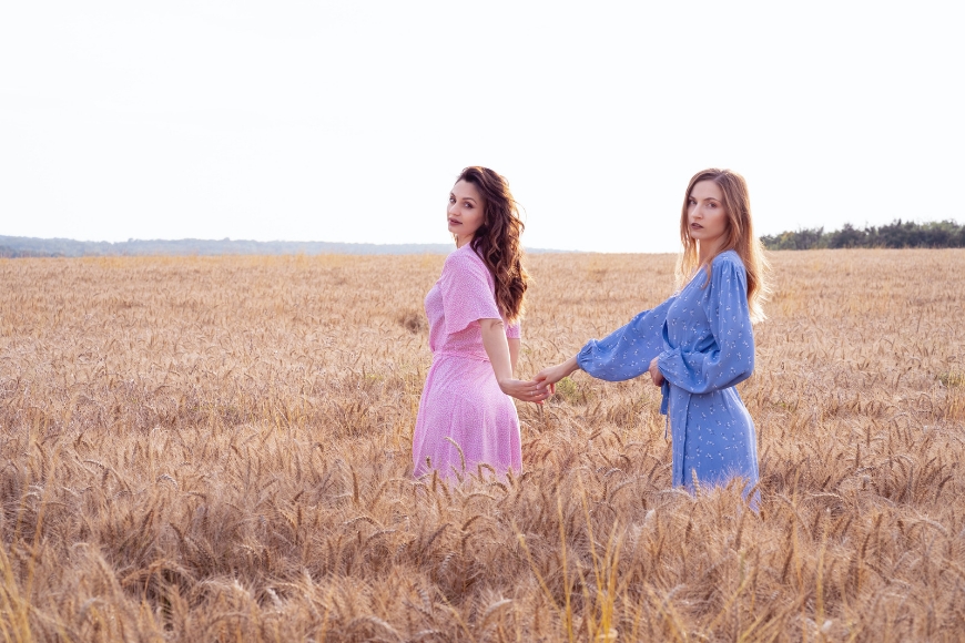 Two young women standing in a wheat field.