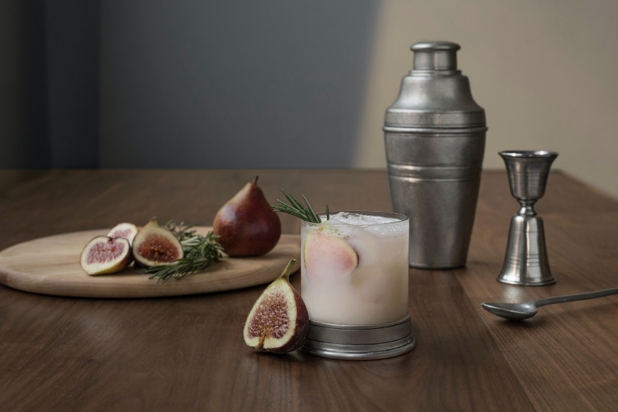 A cocktail with figs on a wooden table.