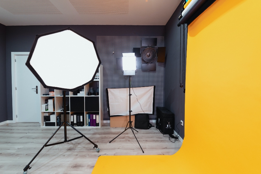 A photo studio with a yellow backdrop and lighting equipment.