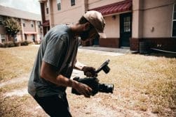A man holding a camera in front of a building.