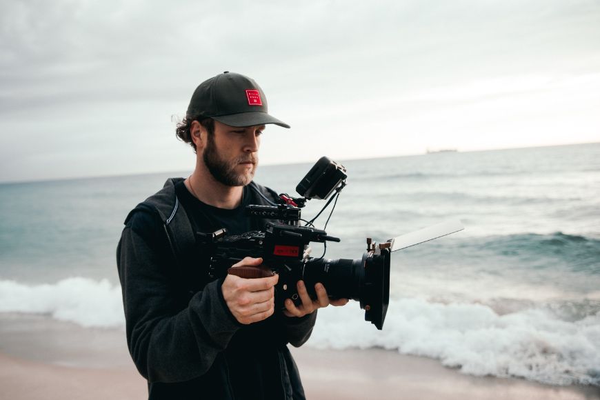 A man holding a camera on the beach.