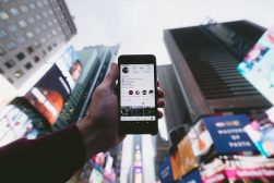A person holding up an instagram phone in front of a city.
