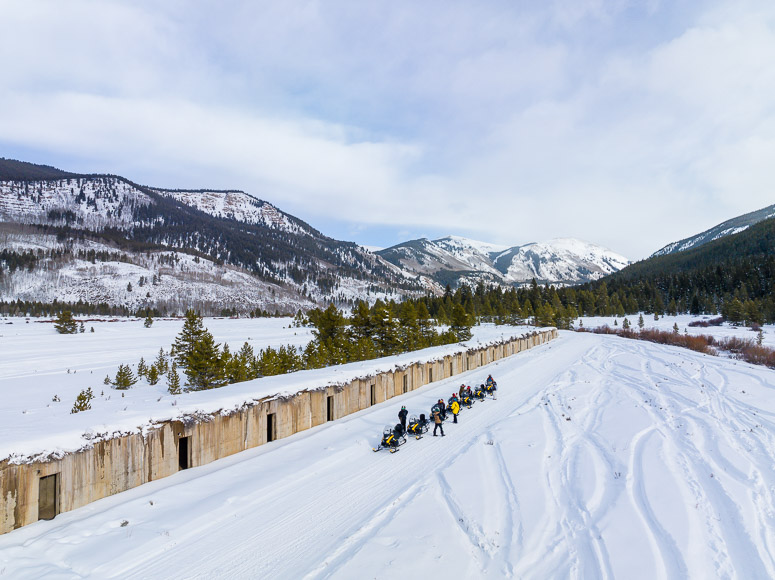 A group of people riding snowmobiles in the snow.