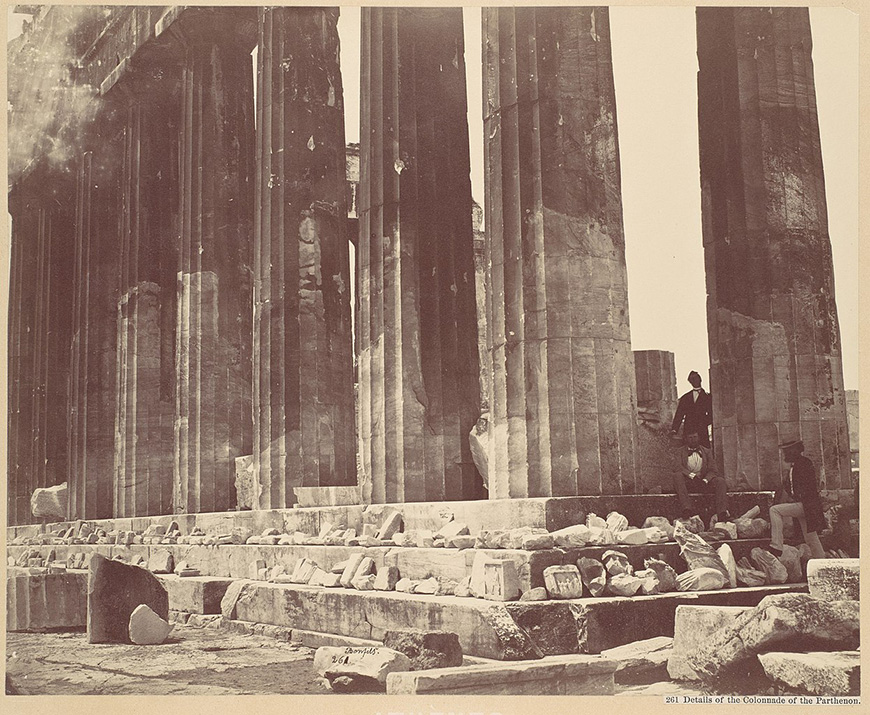 An old photo of a group of people standing in front of pillars.