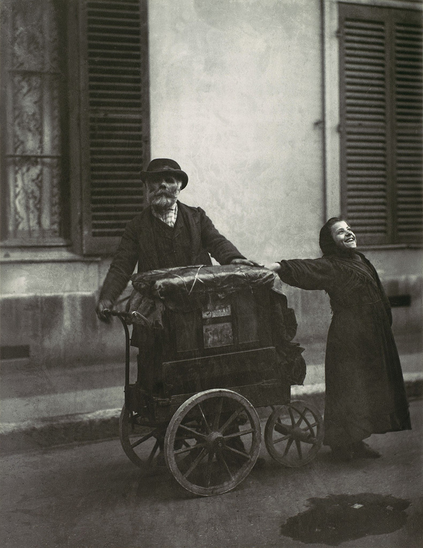 An old photo of a man and woman pushing a cart.