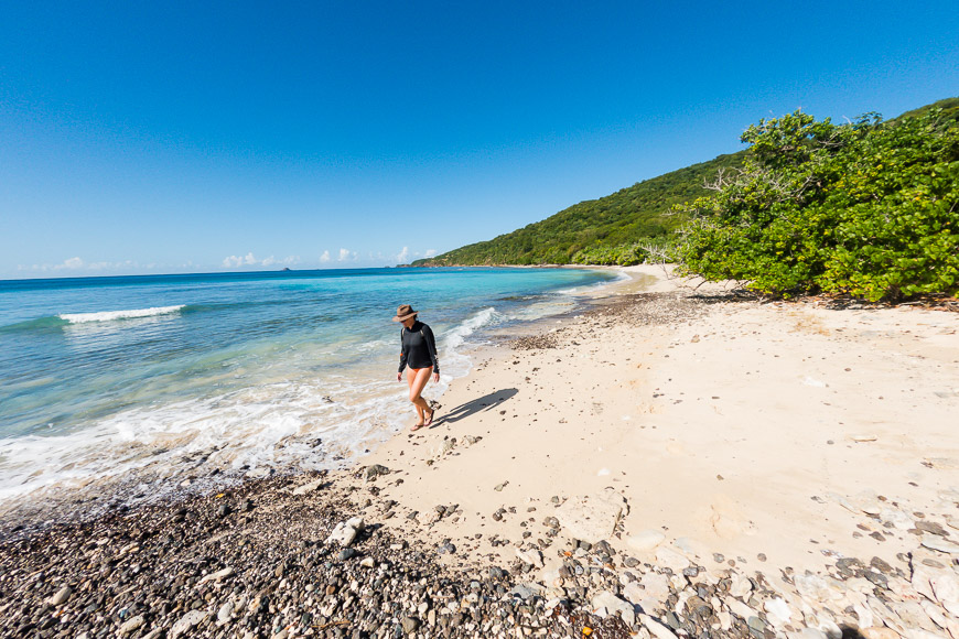 A woman walking on a sandy beach near the ocean.