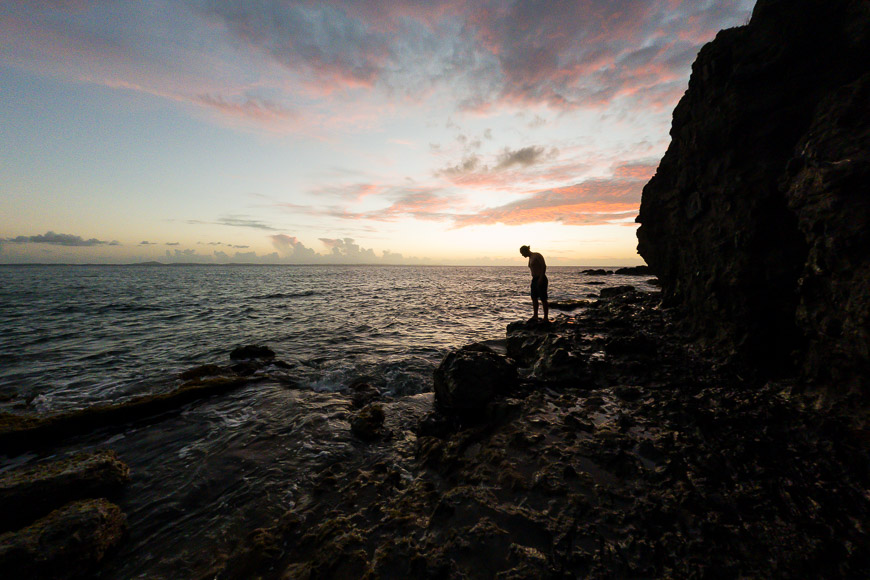 A person standing on a rocky cliff overlooking the ocean.