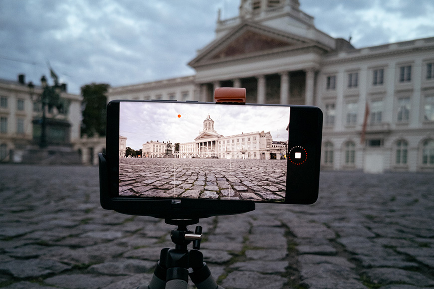 A smartphone with a tripod in front of a building.