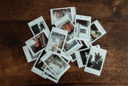 A pile of photos on a wooden table.