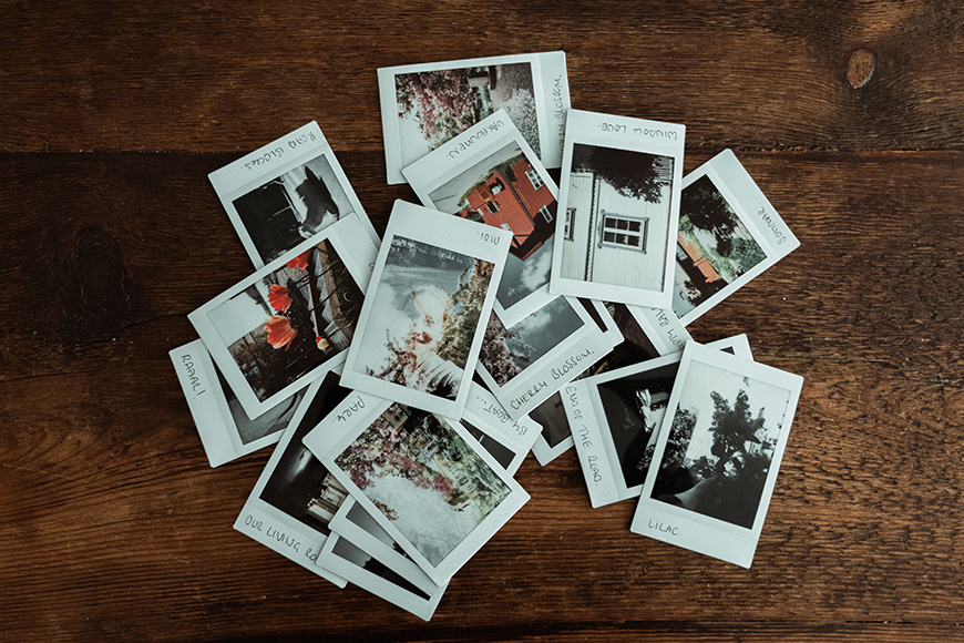 A pile of photos on a wooden table.
