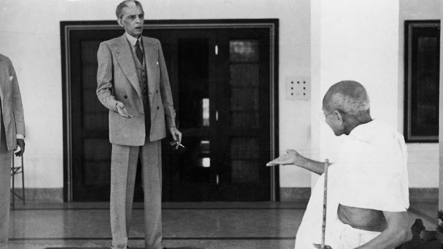Gandhi speaks to a man in a suit.