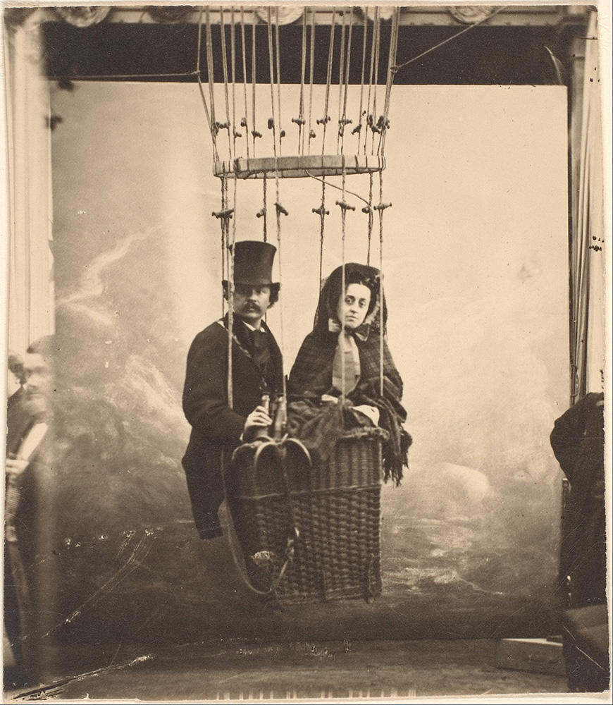 A man and woman in a basket on a hot air balloon.