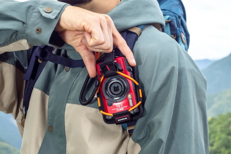 A man is holding a camera in his backpack.