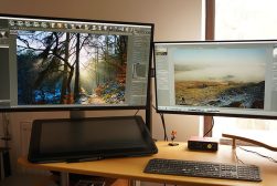 A desk with two monitors showing RawTherapee and Darktable software.