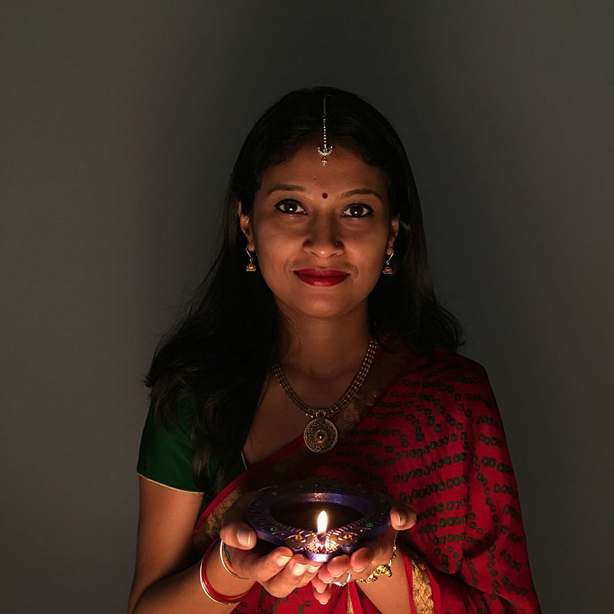 A woman in a sari holding a candle.
