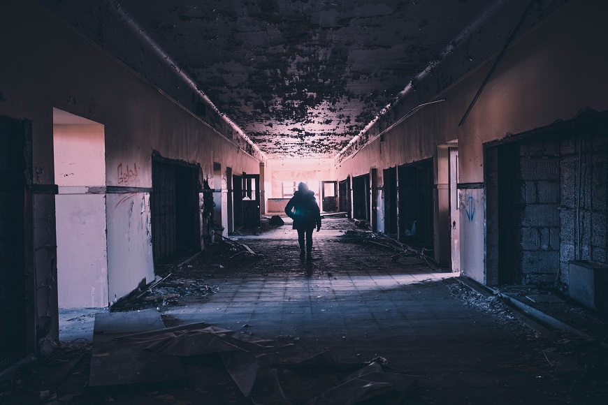 A person walking down an empty hallway in an abandoned building.