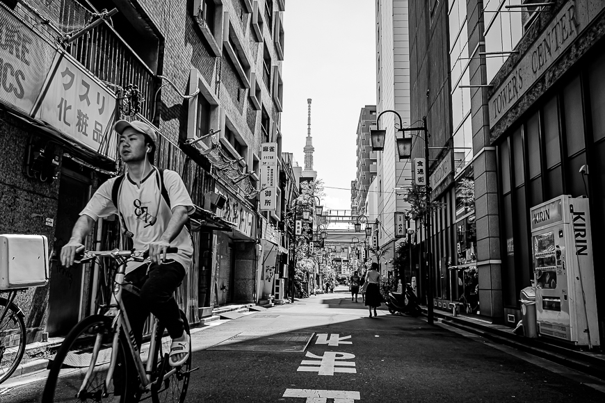 A man riding a bicycle down a street in tokyo.