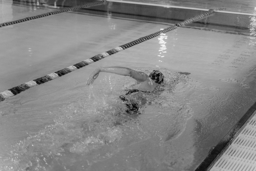 Black and white photo of a swimmer swimming in a pool.
