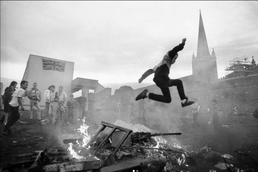 A man jumps over a fire in front of a crowd.