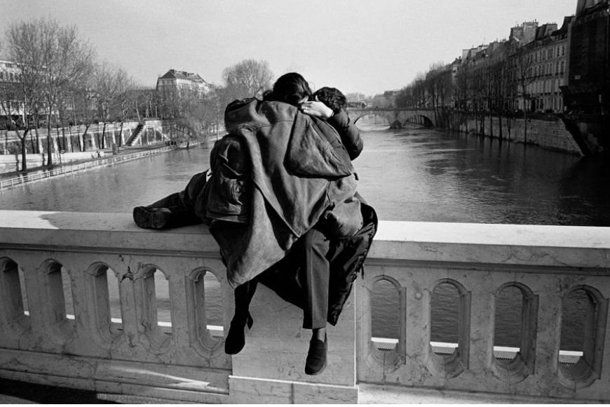 A black and white photo of a couple on a bridge.