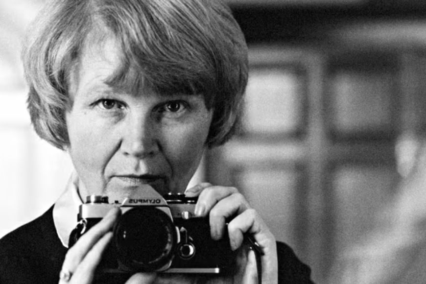 A black and white photo of a woman holding a camera.