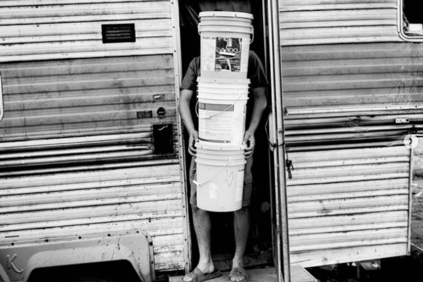 A black and white photo of a person standing in the door of a rv.