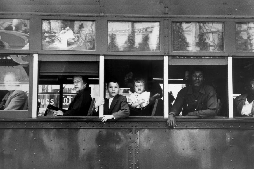 A black and white photo of people on a bus.