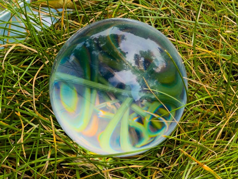A glass ball laying in the grass.
