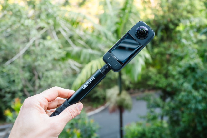 A person holding up an Insta360 x3 action camera on invisible selfie stick.