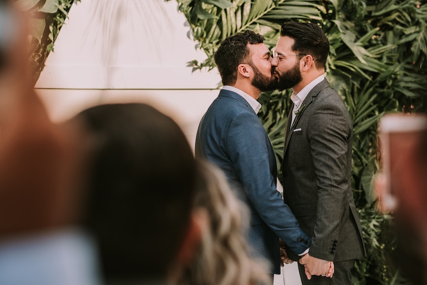 Two men kissing in front of a crowd of people.