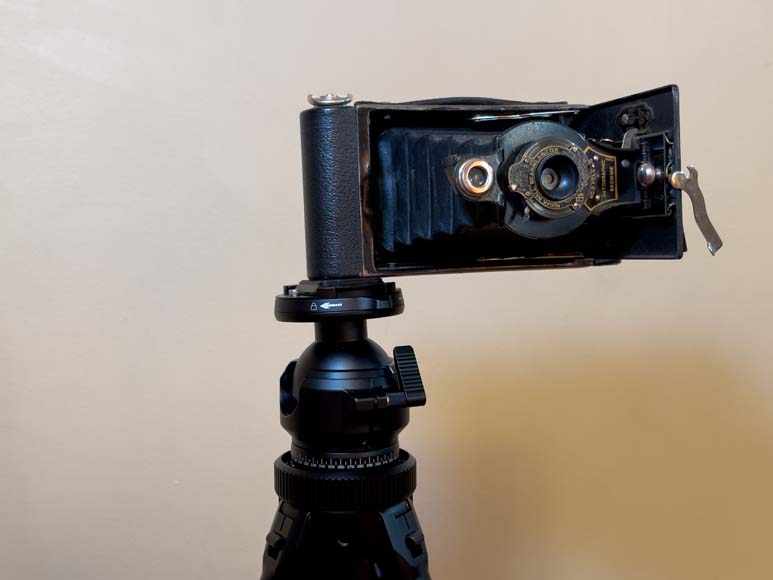 An old camera on top of a tripod.