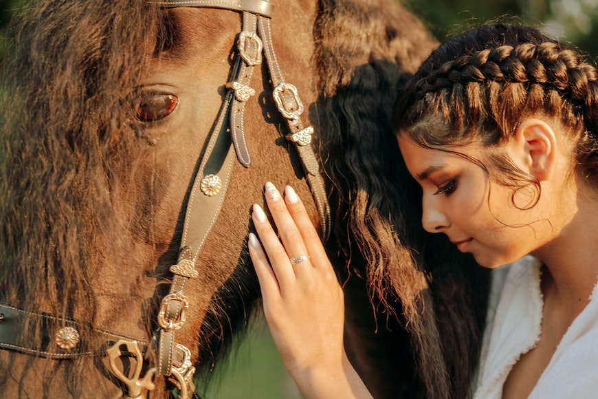A woman is petting a horse in a field.