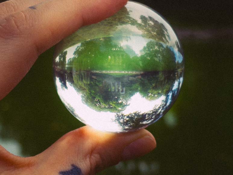 A person holding a glass ball with a reflection in it.