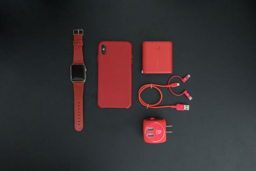 A red phone and other accessories laid out on a black surface.