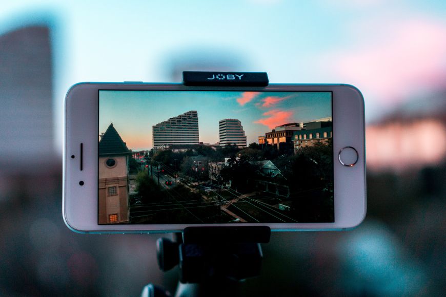 A cell phone with a tripod in front of a city.