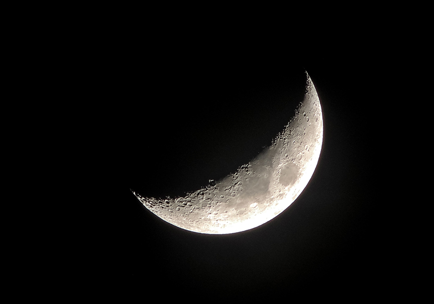 A crescent moon is seen in the dark sky.