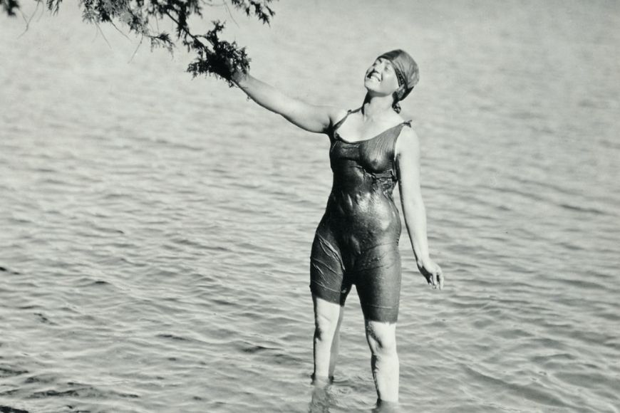 A woman in a bathing suit standing in the water.