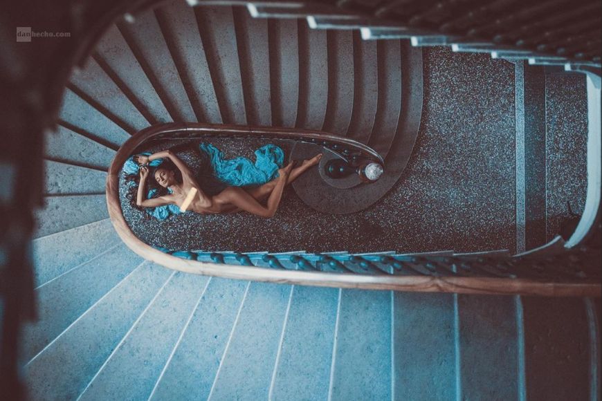 A woman is laying down on a spiral staircase.