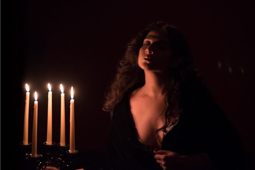 A woman holding candles in front of a dark room.