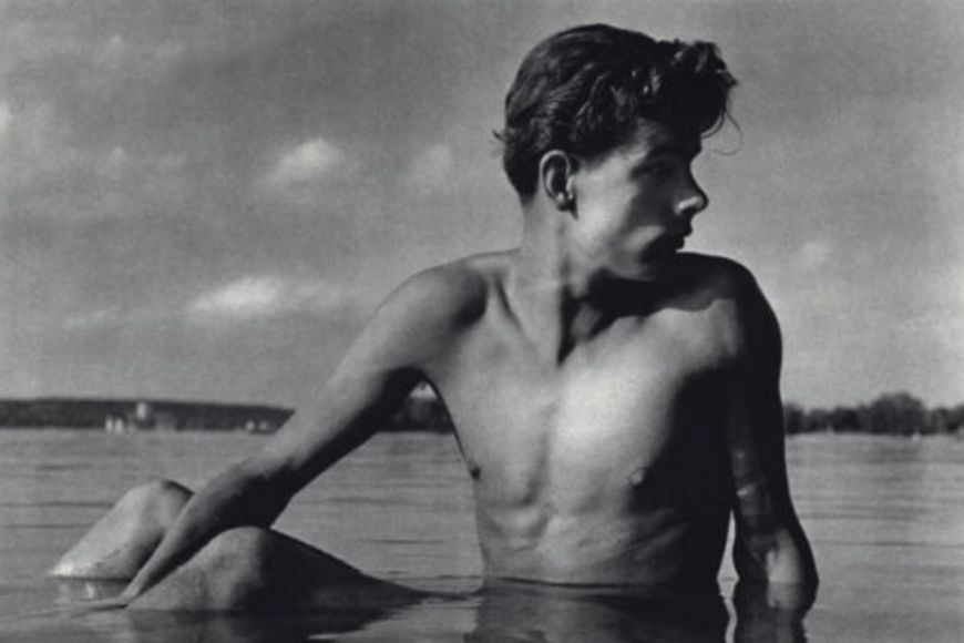 A black and white photo of a young man in the water.