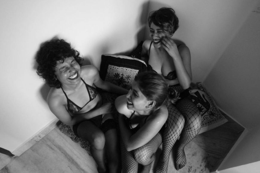 Three women in lingerie sitting on the floor.