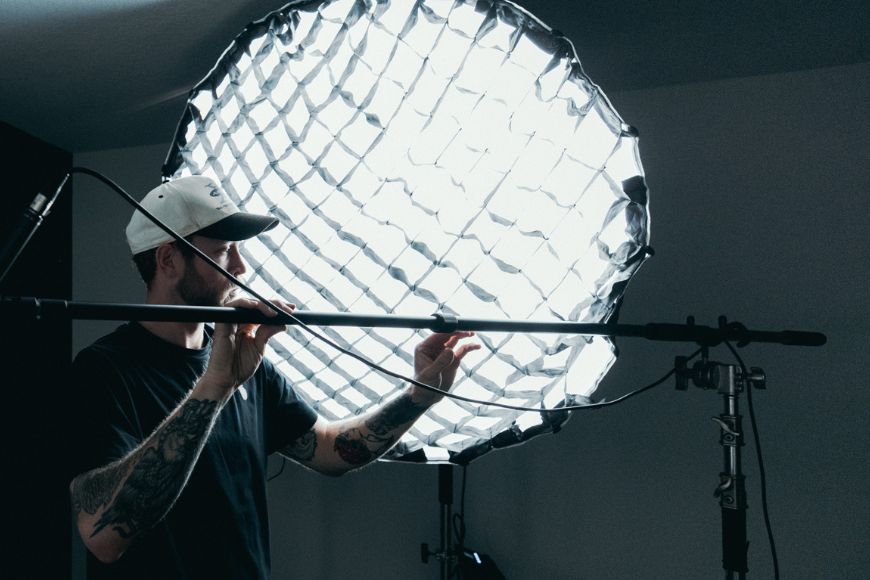 A man in a studio setting up a light.