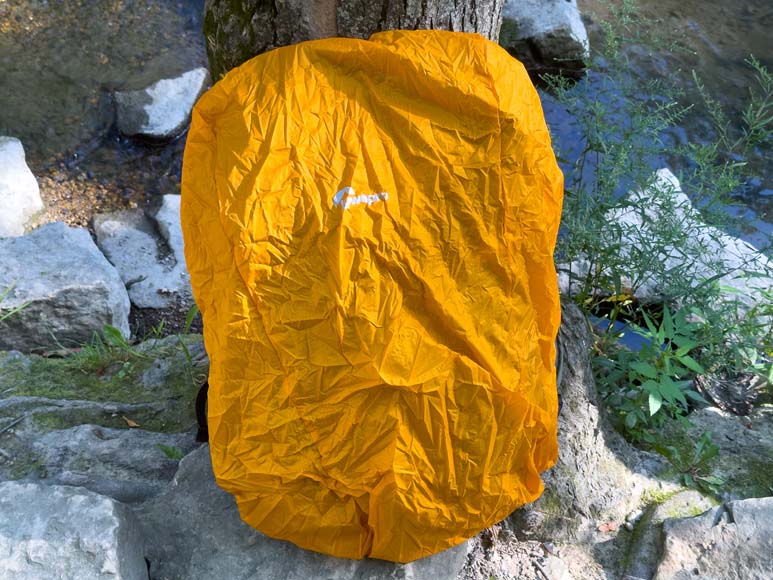 A yellow backpack sitting on a rock next to a stream.