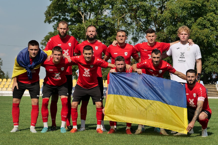 A group of men posing for a photo with a ukrainian flag.