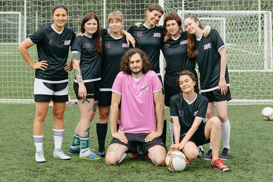 A group of women posing for a picture on a soccer field.